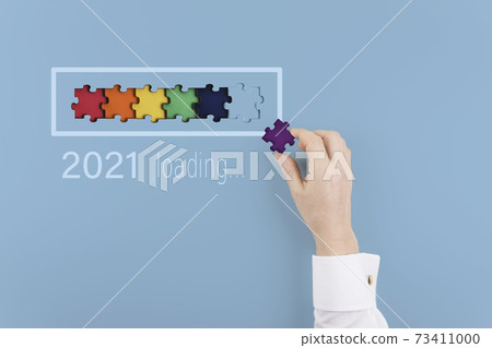 Loading new year 2021 with man hand putting part of puzzle in progress bar. Creative background for the new year. Copy space. 73411000