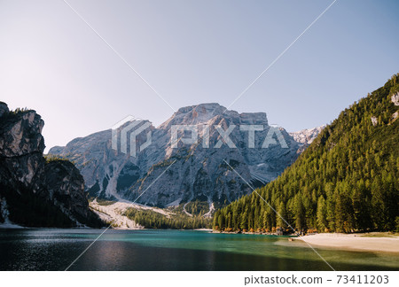 Rocky mountains with green forests at Lago di Braies. Braies lake in the Dolomites in South Tyrol, Italy, a municipality of Braies, in the Prague Valley. Rocky mountains with green forests at Lago di Braies. Braies lake in the Dolomites in South Tyrol, Italy, a municipality of Braies, in the Prague Valley. 73411203