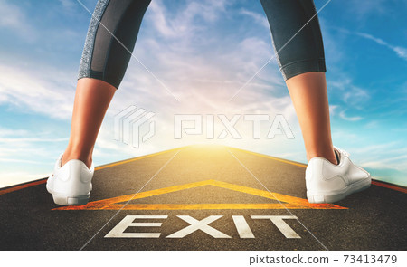 Woman standing on exit signage road for Business exit strategy concept with blue sky background. Woman standing on exit signage road for Business exit strategy concept with blue sky background. 73413479