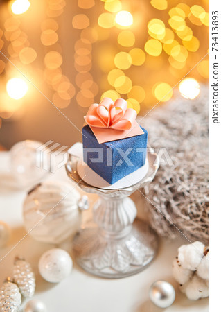 Mini mousse pastry dessert with blue velour. garland lamps bokeh background. In the form of gift box, ribbons of chocolate. Modern european cake. French cuisine. Christmas theme Mini mousse pastry dessert with blue velour. garland lamps bokeh background. In the form of gift box, ribbons of chocolate. Modern european cake. French cuisine. Christmas theme 73413893