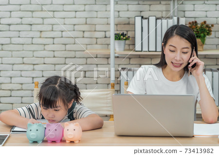 Asian mother is teaching her daugther about financial saving and business while working at home. 73413982