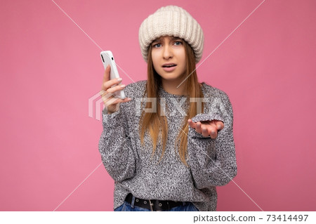 Beautiful angry upset young blonde woman wearing casual grey sweater and beige hat isolated over 73414497