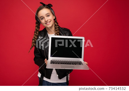 Photo of beautiful happy smiling girl with brunet pigtails holding computer laptop wearing black Photo of beautiful happy smiling girl with brunet pigtails holding computer laptop wearing black 73414532