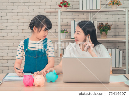 Asian mother is teaching her daugther about financial saving and business while working at home. 73414607