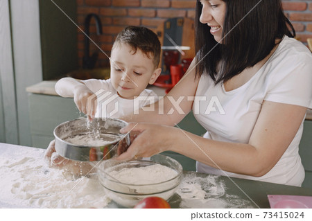 Family in a kitchen cook the dough for cookies Family in a kitchen cook the dough for cookies 73415024