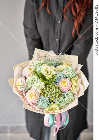 Beautiful bouquet of mixed flowers on women hand. the work of the florist at a flower shop. Delivery fresh cut flower. European floral shop. 73415085