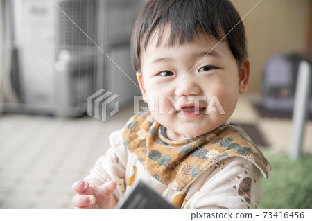 Baby laughing with a remote control 73416456