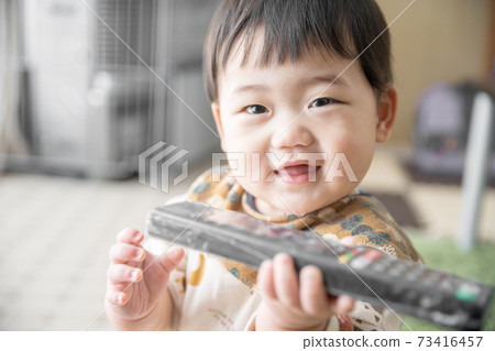 Baby laughing with a remote control 73416457