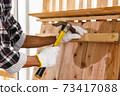 Carpenter use hammer on timber in carpentry workshop. 73417088