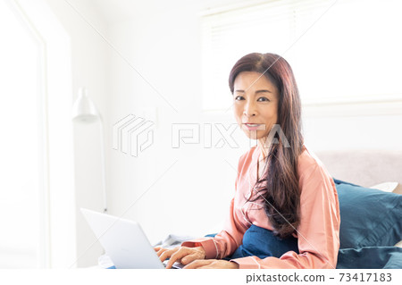 A woman who takes a computer at bed 73417183