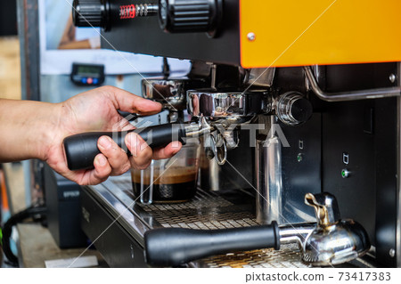 Espresso pouring machine with barista hand close up Espresso pouring machine with barista hand close up 73417383