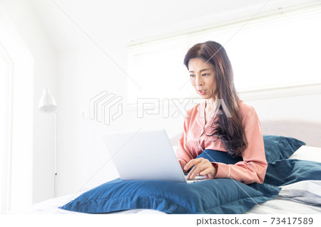 A woman who takes a computer at bed A woman who takes a computer at bed 73417589