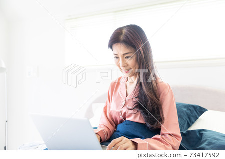 A woman who takes a computer at bed A woman who takes a computer at bed 73417592