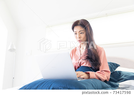 A woman who takes a computer at bed A woman who takes a computer at bed 73417598