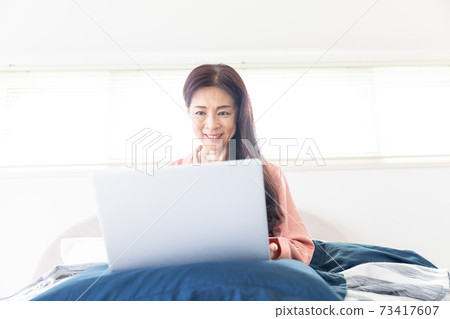 A woman who takes a computer at bed A woman who takes a computer at bed 73417607