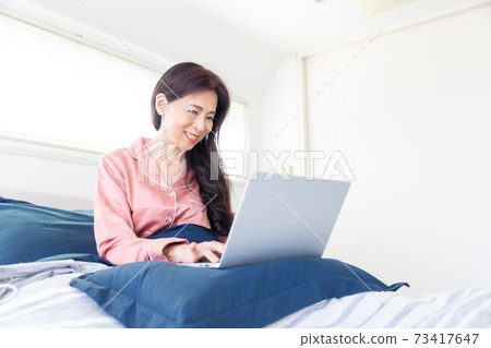 A woman who takes a computer at bed A woman who takes a computer at bed 73417647
