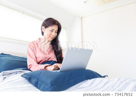 A woman who takes a computer at bed A woman who takes a computer at bed 73417652