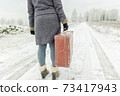 Woman with vintage suitcase in winter 73417943