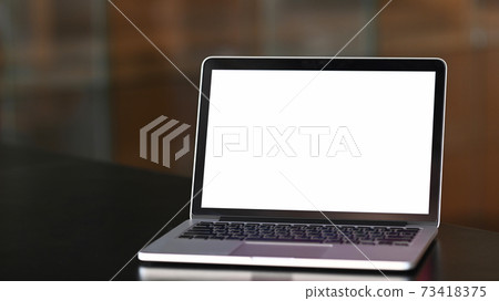 An open mock up laptop computer with blank white screen on black wooden table at conference room. An open mock up laptop computer with blank white screen on black wooden table at conference room. 73418375