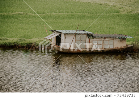 Cinematic scenery of a wooden boat house moored in the riverside of Ninh Binh, Vietnam 73419735