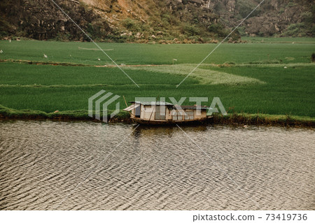 Cinematic scenery of a wooden boat house moored in the riverside of Ninh Binh, Vietnam Cinematic scenery of a wooden boat house moored in the riverside of Ninh Binh, Vietnam 73419736