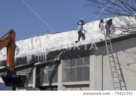 People who remove the snow from the roof 73422391
