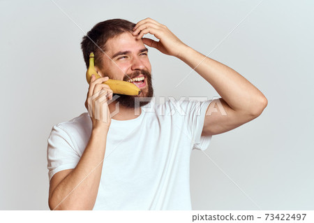 Cheerful man with a banana in his hands on a light background fun emotions Cropped view Copy Space Cheerful man with a banana in his hands on a light background fun emotions Cropped view Copy Space 73422497