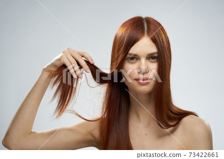 pretty redhead woman holding her hair with hands grooming naked shoulders light background pretty redhead woman holding her hair with hands grooming naked shoulders light background 73422661