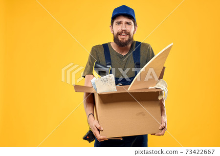 A man in a working form a box with loading tools yellow background A man in a working form a box with loading tools yellow background 73422667