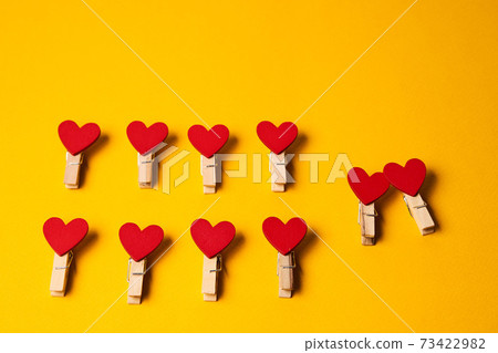 Red clothespins in the form of hearts on a yellow background close-up number of items 73422982