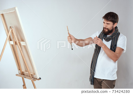 A man artist draws on an easel a scarf white t-shirt art hobby creativity 73424280