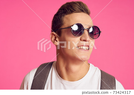 Man in sunglasses with a backpack white t-shirt youth style pink background Man in sunglasses with a backpack white t-shirt youth style pink background 73424317