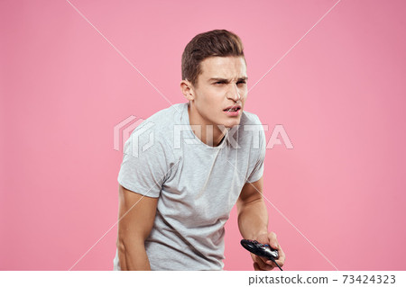 Cheerful man with joystick wire technology entertainment lifestyle pink background Cheerful man with joystick wire technology entertainment lifestyle pink background 73424323