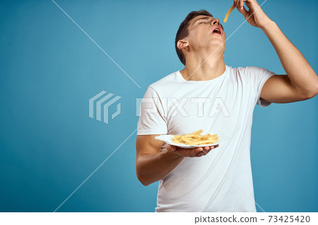 man with fries in cardboard plate calories fast food blue background teen model cropped view man with fries in cardboard plate calories fast food blue background teen model cropped view 73425420