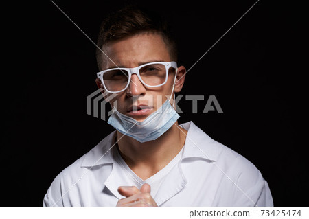 doctor in protective medical mask and glasses on black background close-up portrait cropped view doctor in protective medical mask and glasses on black background close-up portrait cropped view 73425474