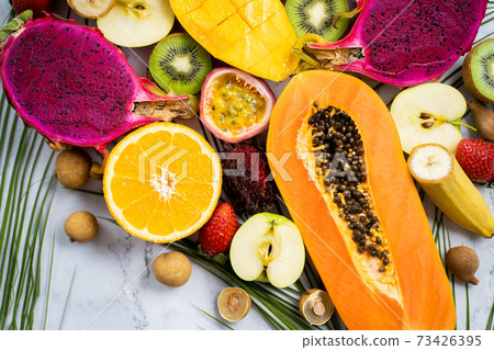 Exotic fruits and tropical leaves on table 73426395