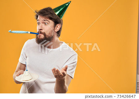 A bearded man with a cake and in a cap celebrating his birthday A bearded man with a cake and in a cap celebrating his birthday 73426647
