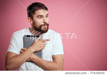 Man advertises a tablet on a pink background codes Space cropped view of emotions white t-shirt model new technologies Man advertises a tablet on a pink background codes Space cropped view of emotions white t-shirt model new technologies 73426649