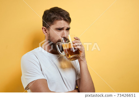 Man with a mug of beer fun alcohol lifestyle white t-shirt yellow isolated background Man with a mug of beer fun alcohol lifestyle white t-shirt yellow isolated background 73426651