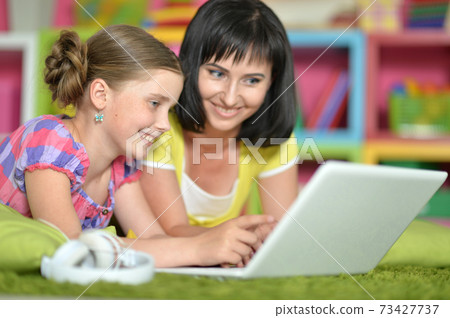 Portrait of smiling mother and daughter using laptop 73427737