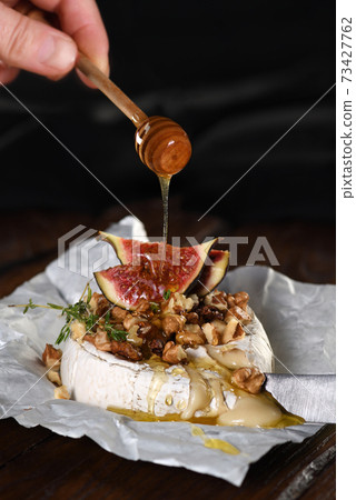 Baked brie cheese with nuts and honey 73427762