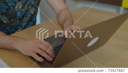Young man using a laptop to send work emails, shop online to navigate on social networks or e-learning. 73427887