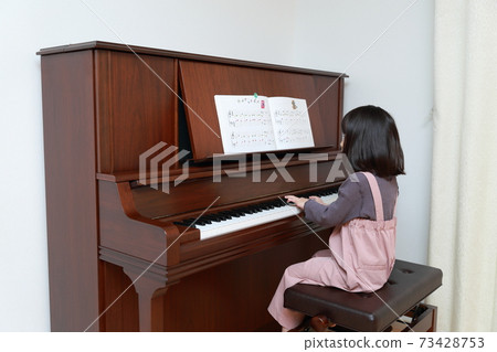 5-year-old girl playing an upright piano 5-year-old girl playing an upright piano 73428753