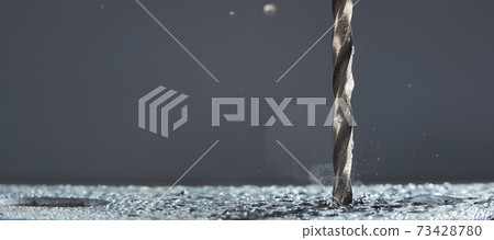 Metal drill bit make holes in metal billet on industrial drilling machine with shavings on gray background. Metal drill bit make holes in metal billet on industrial drilling machine with shavings on gray background. 73428780