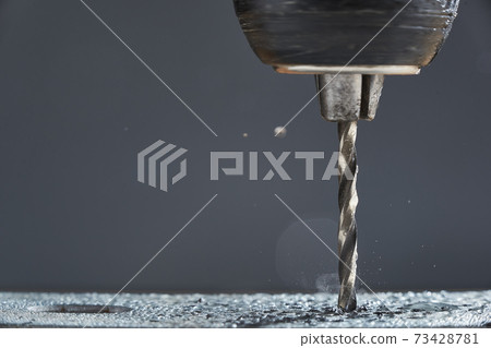 Metal drilling closeup in metal workshop on gray background. Hole being drilled into metal. Metal drilling closeup in metal workshop on gray background. Hole being drilled into metal. 73428781