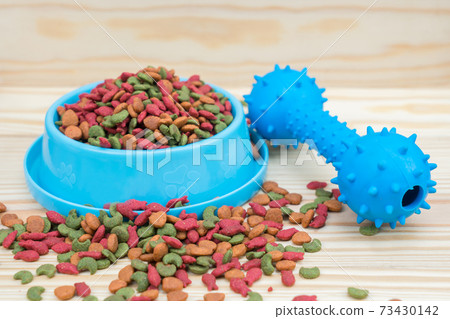 Rubber toy and dry food for pet on wooden background 73430142