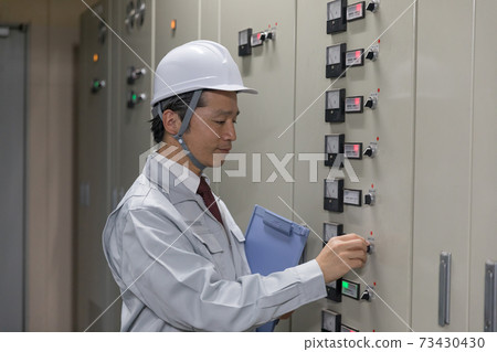 Middle man operating the switchboard in the factory facility Middle man operating the switchboard in the factory facility 73430430