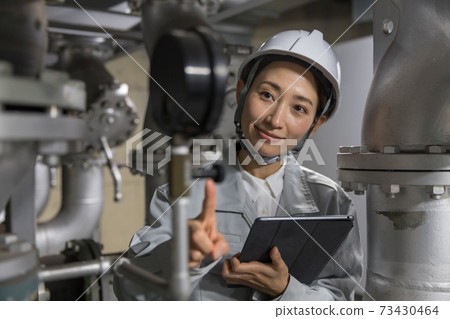 Business woman performing equipment maintenance at factory facilities 73430464
