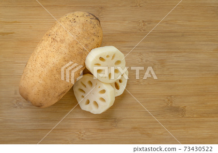 Whole lotus root and sliced lotus roots which put together on wooden cutting board, top view image for flat lay design, space for copy. Whole lotus root and sliced lotus roots which put together on wooden cutting board, top view image for flat lay design, space for copy. 73430522