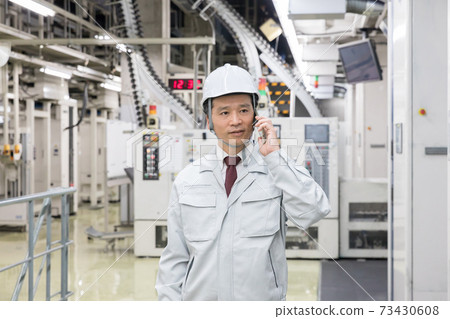 A man who uses a smartphone in the factory 73430608